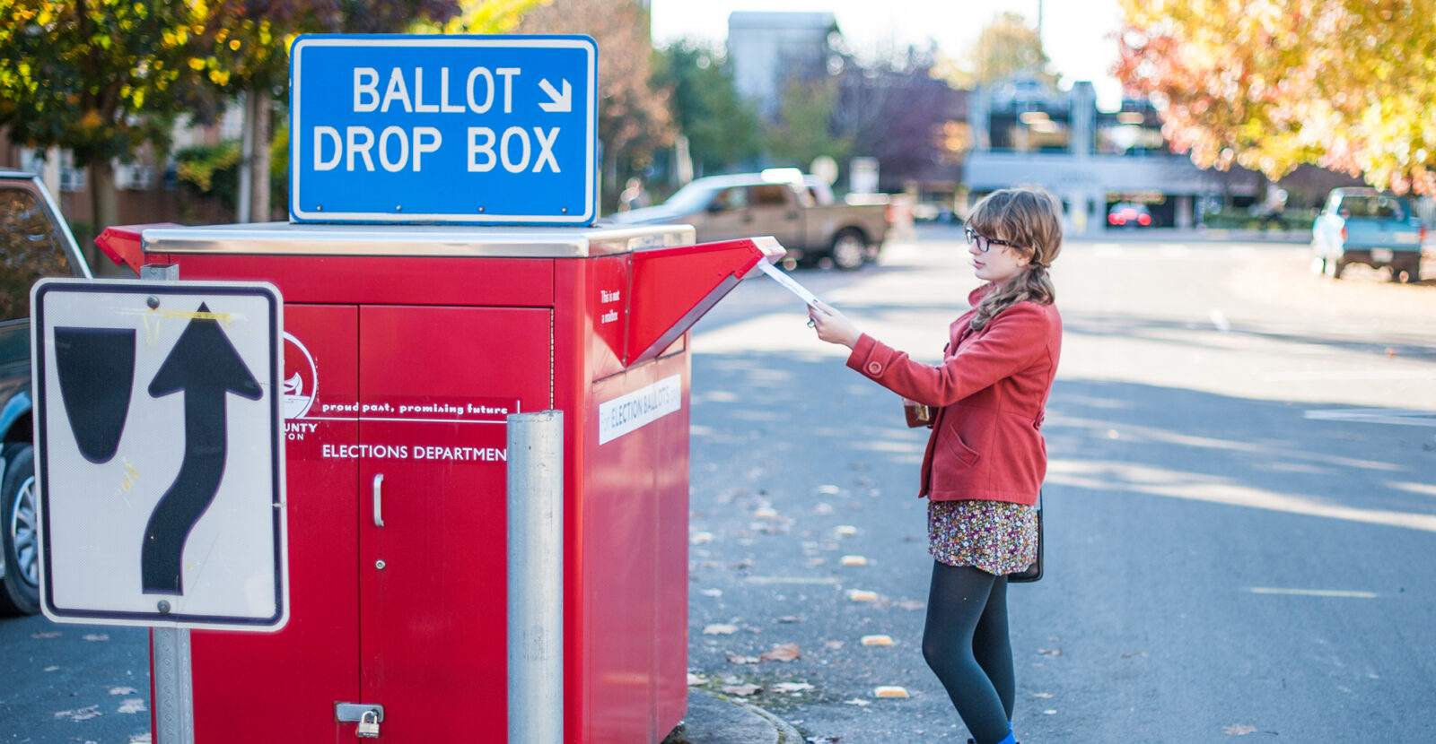 person dropping their election ballot in a drop box